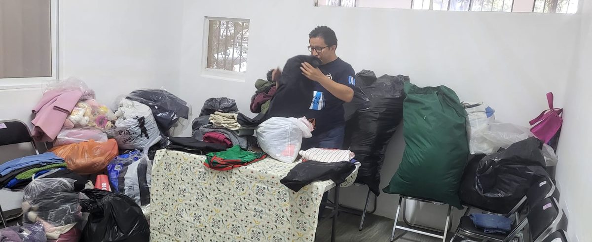 Voluntario acomodando ropa donada en el centro de acopio